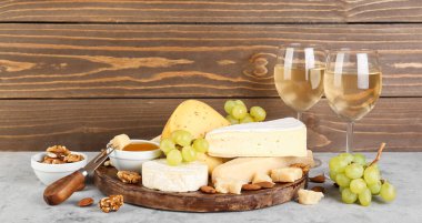 Farklı peynir türleri, şarap ve üzümlü bardaklar.