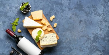 Farklı çeşitlerde lezzetli peynir ve şarap ile mavi arka planda.