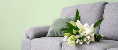 Gri kanepede bir buket nilüfer çiçeği şık oturma odasında, yakın plan.