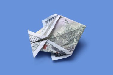 Mavi arka planda dolar banknotundan yapılmış Origami balığı