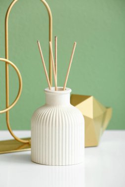 Renkli duvarın yanındaki masada dekorlu bir şişe sazlık ayırıcı, yakın plan.