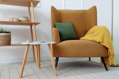Brown armchair, coffee table and shelving unit near white wall