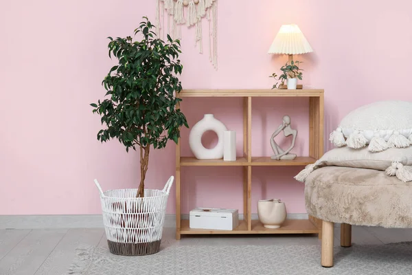 Rafa kaldırma ünitesi, yastıklı puf ve beyaz tuğla duvarın yanındaki ev bitkisi.