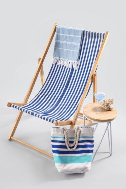 Güverte sandalyesi, plaj aksesuarları, kokteyl ve mercan gri arka planda.