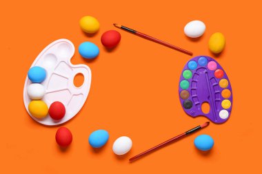 Renkli paletler, Paskalya yumurtaları ve fırçalardan yapılmış çerçeve. Paskalya konsepti.