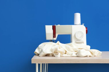 Mavi arka planda kumaşı olan modern dikiş makinesi