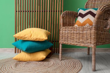 Odanın içi ahşap perdeli, hasır koltuklu ve yeşil duvarlı yastıklı.