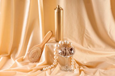 Saç spreyi, fırça, inci kolye ve sarıda saç bandı.