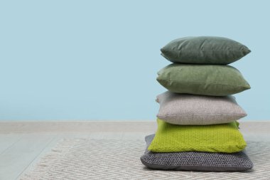 Mavi duvarın yanındaki odada yastık yığını var.