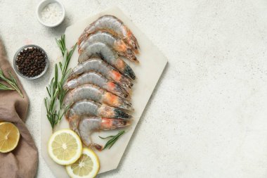 Beyaz arka planda taze çiğ karides, limon ve biberiye.