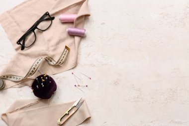 Gözlüklü kompozisyon ve beyaz arka planda dikiş aksesuarları. Üst görünüm