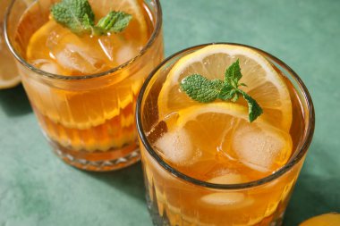 Yeşil arka planda lezzetli soğuk buzlu çay bardakları, yakın plan.