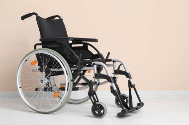 Bej duvarın yanındaki boş tekerlekli sandalye.