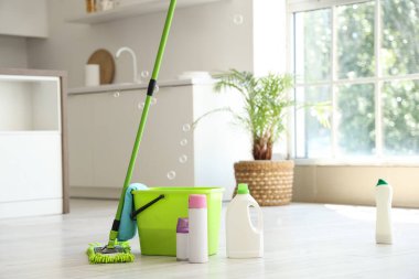 Kovalı paspas, farklı temizlik malzemeleri ve evde yerde sabun köpükleri.