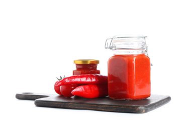 Beyaz arka planda kırmızı biberli domates sosu kavanozları.