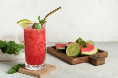 Bir bardak taze karpuz suyu, beyaz arka planda limon ve nane.