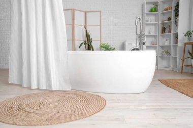 Banyonun içindeki beyaz tuğla duvarın yanındaki perdeli küvet.