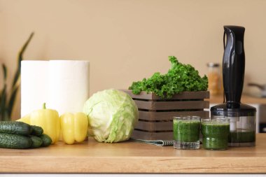 Mutfaktaki masada farklı taze sebzeler ve meyvelerle sağlıklı yeşil meyve suyu.