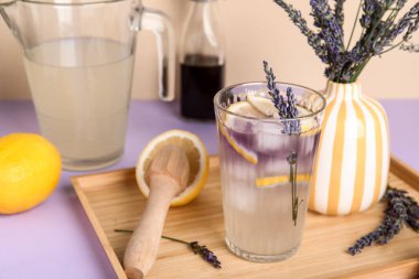 Çiçekli taze lavantalı limonata ve renkli arka planda ahşap sıkacağı.
