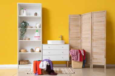 Lavabosu, çamaşır sepetleri ve katlanır perdesi olan şık bir banyo.