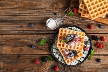 Farklı taze meyveli Belçika waffle tabağı ve ahşap zemin üzerinde nane.