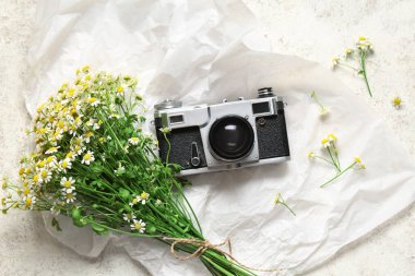 Klasik fotoğraf makinesi, buruşmuş kağıt ve açık arkaplanda güzel papatya çiçekleri.
