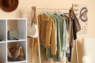 Giysilerle, koltukla ve soyunma odasındaki bej duvarın yanındaki raflarla dolu.