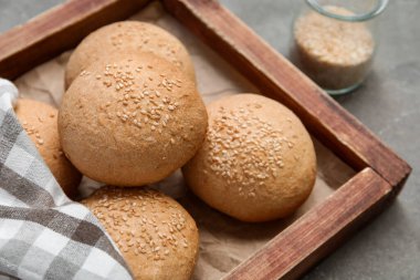 Gri arka planda susam tohumlu taze çörekler.