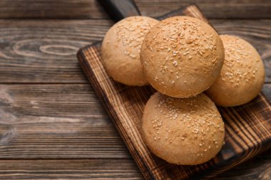 Tahta zemin üzerinde susam tohumları olan taze çörekler.