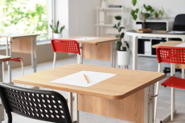 Boş sınıftaki masada bir sayfa kağıt ve kalem. Yakın çekim.