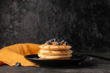 Siyah arka planda taze yaban mersini ve fındıklı bir tabak tatlı krep.