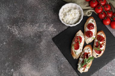 Gri arka planda ricotta soslu lezzetli domates bruschetta.