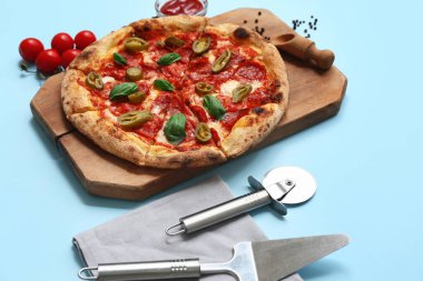 Lezzetli pizzalı kompozisyon, malzemeler ve mavi arka planda kesici.