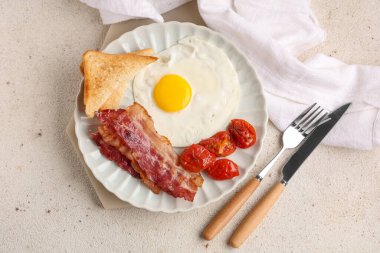 Beyaz arka planda kızarmış yumurta, pastırma, tost ve kurutulmuş domates tabağı. Üst görünüm