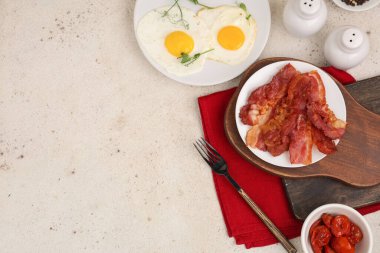 Beyaz arka planda kızarmış yumurta ve pastırma tabakları. Üst görünüm