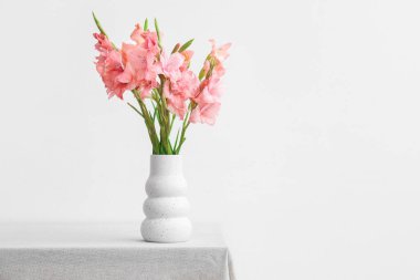 Masada beyaz arka planda duran bir vazo dolusu güzel gladiolus çiçekleri.