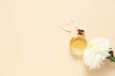 Bej arka planda bir şişe parfüm, kasımpatı ve taç yaprakları.