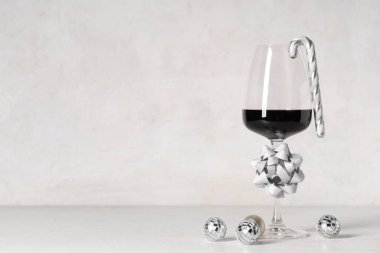 Beyaz grunge arka planda Noel süslemeleri ve şeker kamışlarıyla bir bardak şarap.