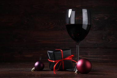 Noel süslemeleri ve ahşap arka planda hediye kutusu olan bir kadeh şarap.