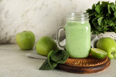 Mason kavanozu beyaz arka planda limonlu ve elmalı taze ıspanaklı smoothie.