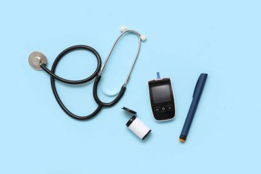 Mavi arka planda neşter ve steteskoplu glukometre. Diyabet kavramı