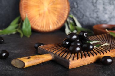 Lezzetli siyah zeytinli ahşap tahta ve siyah arka planda yapraklar.