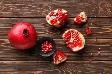 Taze olgun nar ve tahtadan arka planda tohumlarla dolu bir kase.