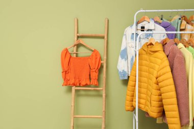 Sonbahar elbiseli raflar ve yeşil duvarın yanındaki merdiven.