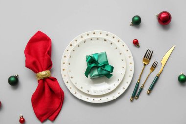 Gri arka planda Noel topları ve hediye kutusuyla güzel bir masa.