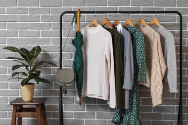 Gri tuğlalı duvarın yanında giysilerle dizilin.