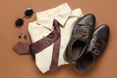 Kahverengi arka planda gömlek ve ayakkabıları olan şık erkek aksesuarları.