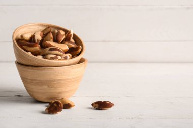 Beyaz ahşap arka planda lezzetli Brezilya fındıkları olan kase.