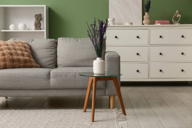 İçinde güzel lavanta çiçekleri ve modern oturma odasının içinde rahat bir kanepe olan vazo.