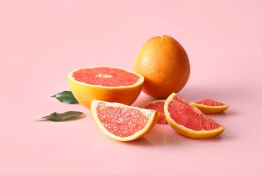 Taze greyfurtlar ve pembe arka planda yapraklar.